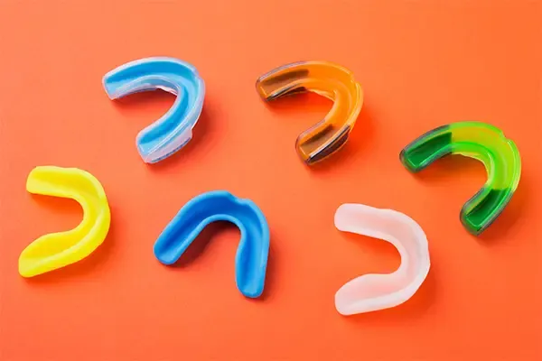 Many sports guards of different colors showcasing the variety of mouth and teeth protection options.
